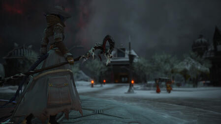 Sarnai, wearing a long gray coat with sheepskin trim and many pockets, as well as a hat and mask that hides much of her face, holds her staff as she looks towards the buildings of Camp Broken Glass.